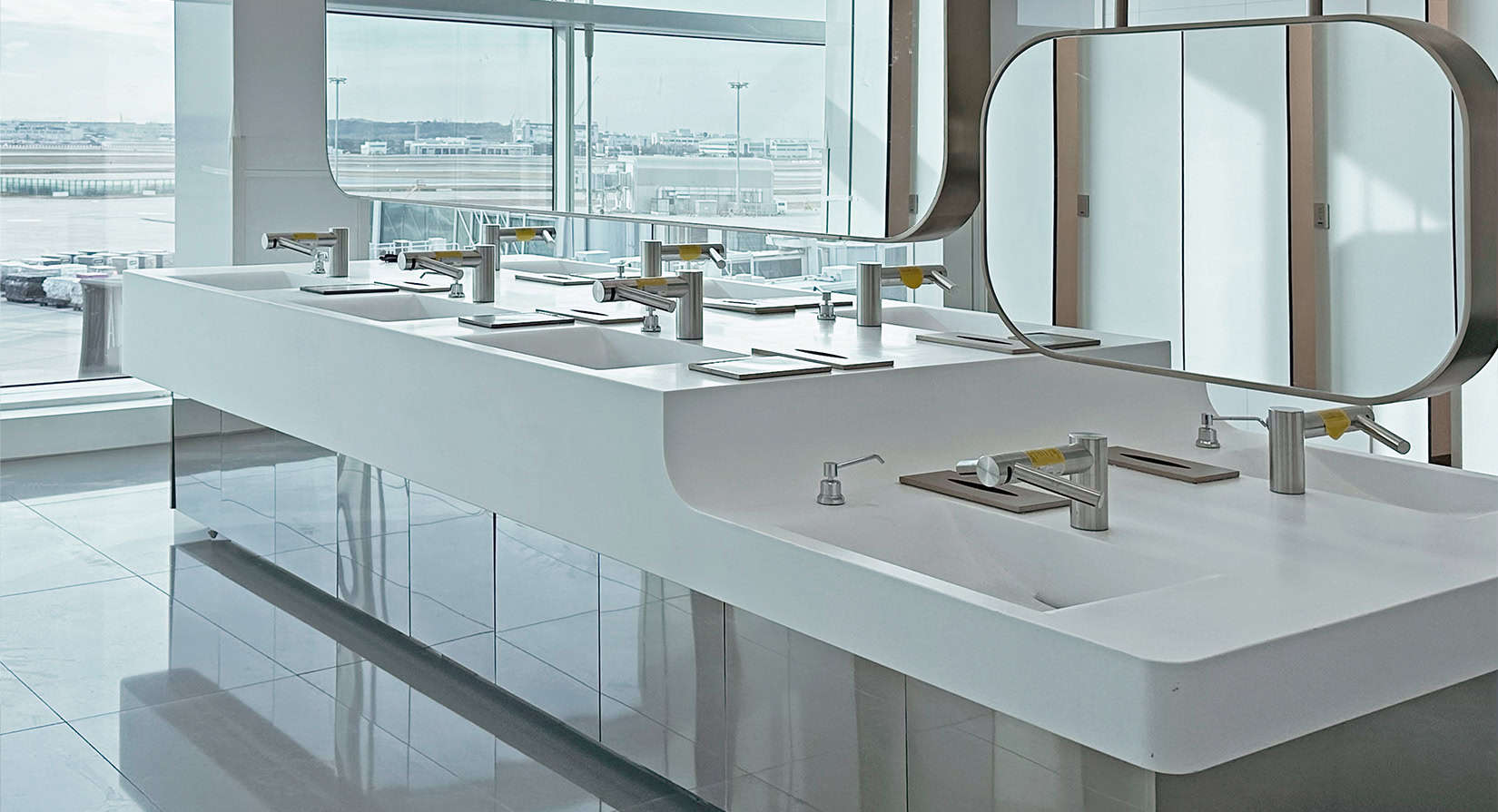 Island style sinks in the centre of the restroom with views of the runway