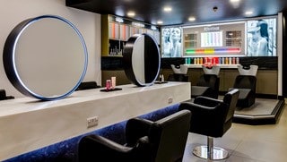 salon with mirrors chairs and white solid surfaces that gives a modern luxury finish