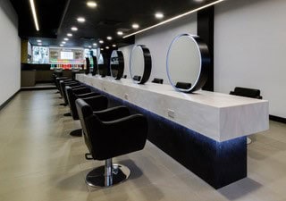 salon with mirrors chairs and white solid surfaces that gives a modern luxury finish