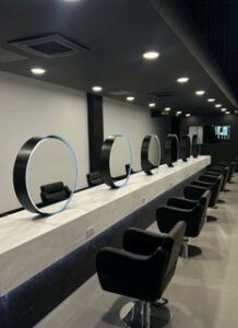 salon with mirrors chairs and white solid surfaces that gives a modern luxury finish