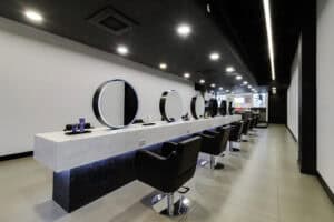 salon with mirrors chairs and white solid surfaces that gives a modern luxury finish
